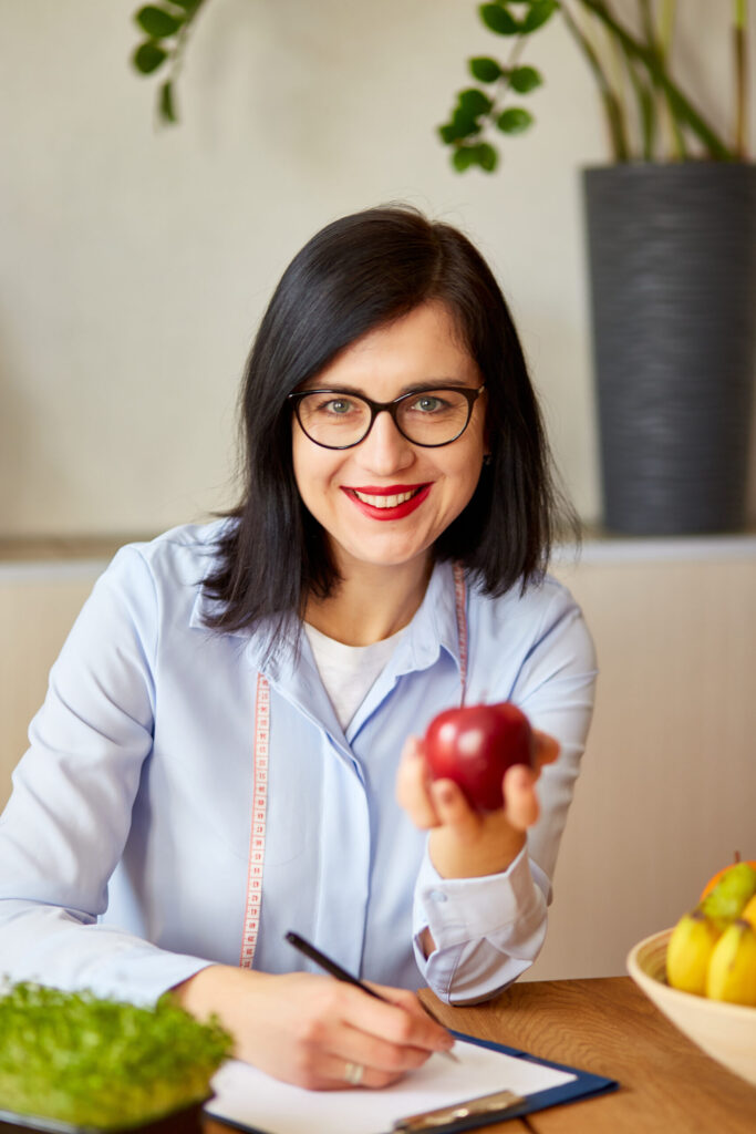 nutritionist, dietitian woman at the office, hold apple in the hand